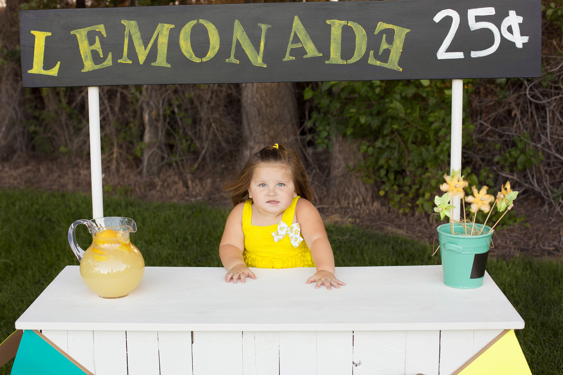 Madison behind the lemonade stand by Pueblo Children's photographer K.D. Elise Photography